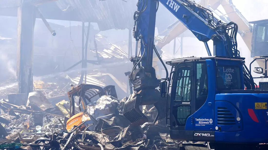 Einsatzkräfte des Technischen Hilfswerks (THW) beseitigen mit einem Bagger Schutt nach einem Feuer in einem Gewerbegebiet in Stuttgart. - Bild: Enrique Kaczor/dpa