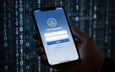 Nahaufnahme einer Hand, die ein Smartphone mit gefälschter Regierungs-Loginseite hält, unscharfer Binärcode-Hintergrund. - Foto: über boerse-global.de
