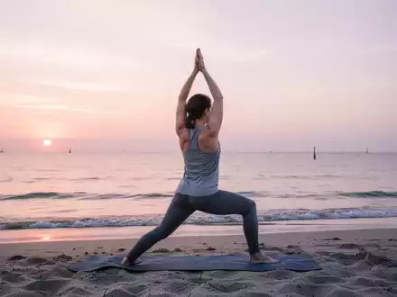 Eine Person macht Yoga in einer friedlichen Pose am Strand von Warnemünde bei Sonnenaufgang mit Blick auf die Ostsee. - Foto: über boerse-global.de