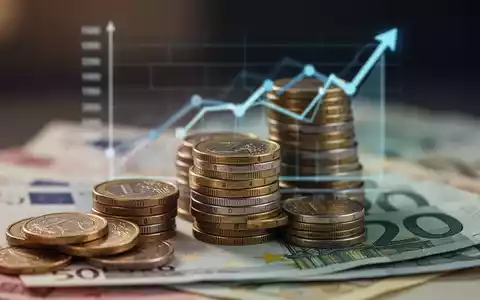 Ein Nahaufnahme-Bild von Euro-Münzen und -Banknoten, mit einem aufsteigenden Diagramm im Hintergrund, das wirtschaftliches Wachstum darstellt. - Foto: über boerse-global.de