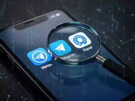 Eine Lupe schwebt über Social-Media-App-Symbolen auf einem Smartphone-Bildschirm, was staatliche Überwachung digitaler Plattformen symbolisiert. - Foto: über boerse-global.de