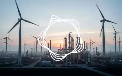 Eine weitläufige industrielle Landschaft bei Sonnenaufgang mit Windturbinen und einer Elektrolyseanlage, die saubere Energieerzeugung symbolisiert. - Foto: über boerse-global.de
