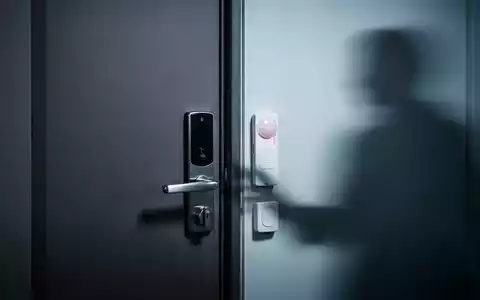Eine Nahaufnahme einer modernen Wohnungstür mit einem Sicherheitsschloss und einem Alarmsensor, gedämpft beleuchtet. - Foto: über boerse-global.de