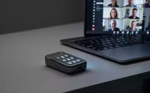 Ein schlankes, modernes Mini-Keypad mit drei beleuchteten Tasten auf einem minimalistischen Schreibtisch neben einem Laptop mit einer Videokonferenz. - Foto: über boerse-global.de