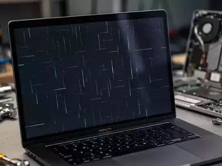Nahaufnahme eines MacBook Pro-Bildschirms mit feinen flackernden Linien, Reparaturwerkzeuge unscharf im Hintergrund. - Foto: über boerse-global.de