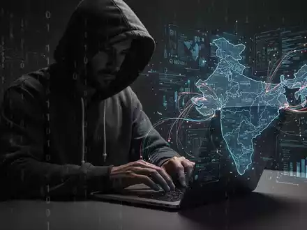 Verschwommene Gestalt im Hoodie tippt auf Laptop, digitale Overlays deuten auf Cyberkriminalität gegen Indien hin. - Foto: über boerse-global.de