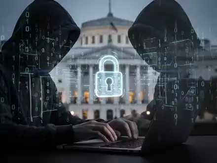 Verschwommene Gestalt in Kapuzenjacke tippt auf Laptop, mit digitalem Code und Schlosssymbol als Hinweis auf KI-Betrug. - Foto: über boerse-global.de