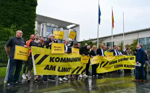 Vertreter mehrerer Städte und Kommunen demonstrieren mit Schildern und Bannern für finanzielle Unterstützung in Berlin. - Foto: Jens Kalaene/dpa