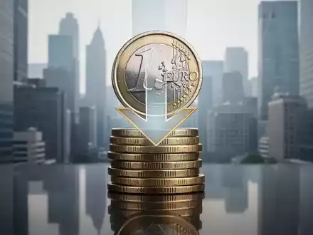Ein stilisierter Turm aus Euro-Münzen mit einem nach unten zeigenden Pfeil vor einer verschwommenen Stadtsilhouette, der Einsparungen symbolisiert. - Foto: über boerse-global.de