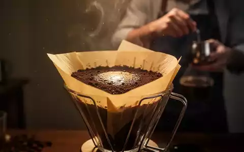 Ein Kaffeefilter mit Kaffeepulver, von hinten beleuchtet, symbolisiert die Filtration von Kaffee und seine Auswirkungen auf die Gesundheit. - Foto: über boerse-global.de