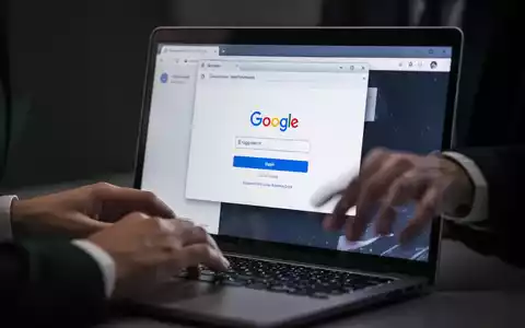 Ein Laptop-Bildschirm zeigt eine gefälschte Google-Login-Seite innerhalb eines Browsers, mit unscharfen Händen über der Tastatur. - Foto: über boerse-global.de