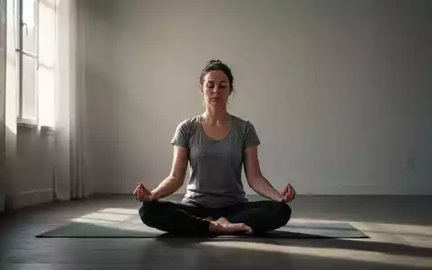 Eine Person sitzt in einer ruhigen, minimalistischen Umgebung in Meditationshaltung, umgeben von sanftem Licht. - Foto: über boerse-global.de