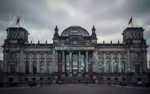 Das Reichstagsgebäude in Berlin unter einem bewölkten Himmel, mit einem dezenten, abfallenden Finanzdiagramm überlagert. - Foto: über boerse-global.de