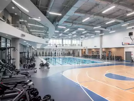 Innenansicht eines modernen Sportvereinszentrums mit Fitnessgeräten, Schwimmbecken und Sporthalle, symbolisiert Investitionen in Sportinfrastruktur. - Foto: über boerse-global.de