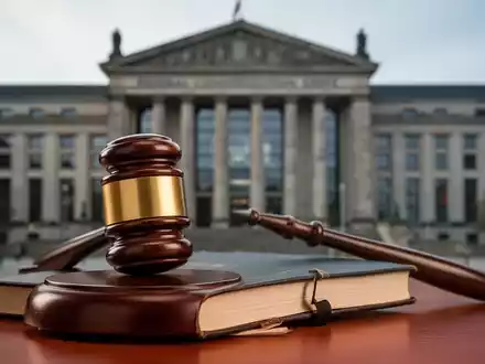Ein stilisierter Hammer auf einem Gesetzbuch, mit dem Bundesverfassungsgericht Karlsruhe im unscharfen Hintergrund. - Foto: über boerse-global.de
