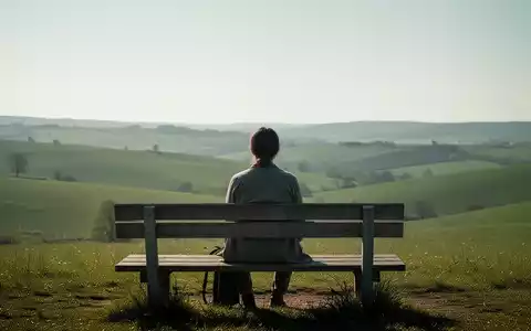 Eine Person sitzt entspannt auf einer Holzbank mit Blick auf eine friedliche, grüne Landschaft, die Ruhe und Einfachheit ausstrahlt. - Foto: über boerse-global.de
