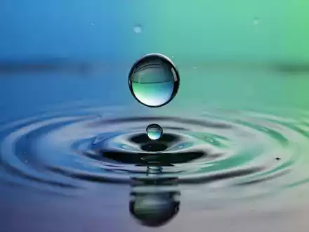Zwei Wassertropfen verschmelzen miteinander auf einer spiegelnden Oberfläche, symbolisierend eine Firmenfusion. - Foto: über boerse-global.de