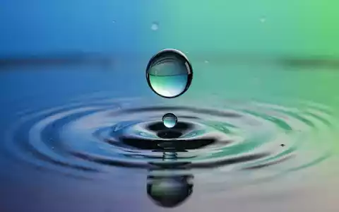 Zwei Wassertropfen verschmelzen miteinander auf einer spiegelnden Oberfläche, symbolisierend eine Firmenfusion. - Foto: über boerse-global.de