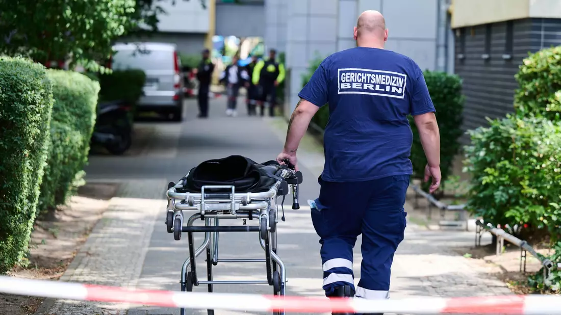 Ein Mann von der Gerichtsmedizin schiebt eine Bahre in der Nähe des Fundortes des toten Neugeborenen. - Bild: Annette Riedl/dpa