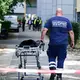 Ein Mann von der Gerichtsmedizin schiebt eine Bahre in der Nähe des Fundortes des toten Neugeborenen. - Bild: Annette Riedl/dpa