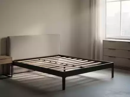 Ein minimalistisches Schlafzimmer mit einem leeren Bettrahmen, Nachttisch und Kommode in neutralen Farben, um eine Sortimentsumstellung anzudeuten. - Foto: über boerse-global.de