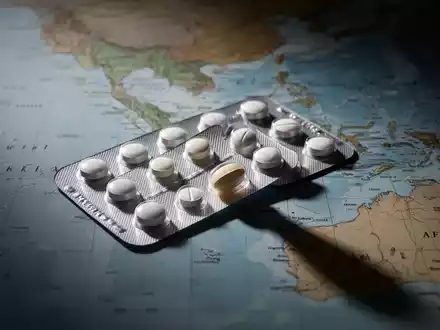 Ein Blisterpackung mit Pillen, eine Pille ist teilweise entfernt. Im Hintergrund eine verschwommene Weltkarte von Südostasien und Afrika. - Foto: über boerse-global.de