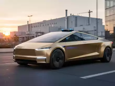 Goldenes Tesla Cybercab Robotaxi auf futuristischer Stadtstraße mit Fabrik im Hintergrund, Symbol für Innovation und Nachhaltigkeit. - Foto: über boerse-global.de