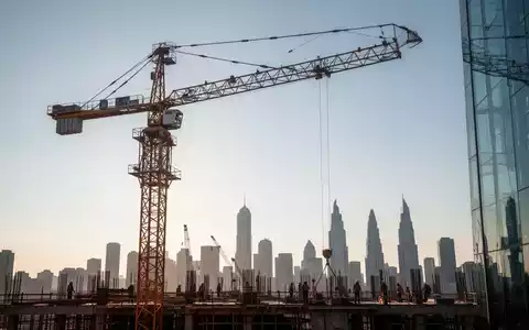 Ein riesiger Bau-Kran vor einem klaren Himmel mit einer Stadtsilhouette im Hintergrund, der moderne Hochbau symbolisiert. - Foto: über boerse-global.de
