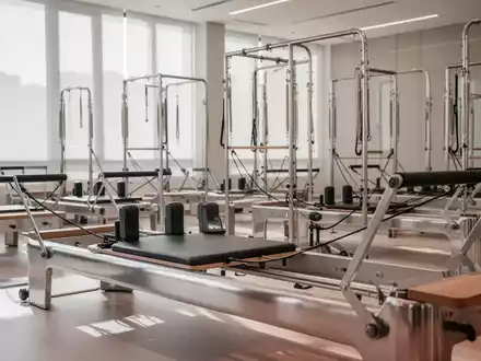 Ein modernes Reformer-Pilates-Studio mit mehreren eleganten Reformer-Geräten in einem hellen, geräumigen Ambiente. - Foto: über boerse-global.de