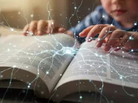 Nahaufnahme eines offenen Buches mit verschwommenem Text und darüberliegenden leuchtenden, abstrakten neuronalen Linien. Eine Kinderhand greift nach dem Buch. - Foto: über boerse-global.de