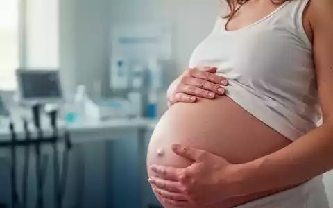 Eine schwangere Frau berührt sanft ihren Bauch, während sie über alternative Schmerzbehandlungen nachdenkt. - Foto: über boerse-global.de