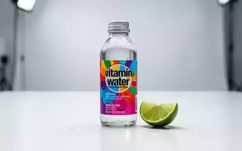 Eine Flasche Vitaminwasser mit einem Limettenschnitz und Wassertropfen auf einer weißen Oberfläche, unscharfer Hintergrund. - Foto: über boerse-global.de