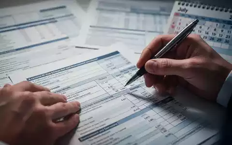Hände füllen ein komplexes Formular aus, Stift über Vermögensabschnitt. Hintergrund verschwommen, Kalender zeigt Juli 2026. - Foto: über boerse-global.de