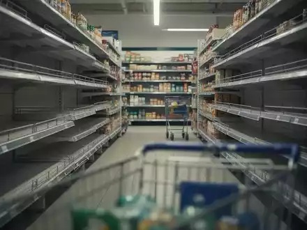 Ein unscharfer Supermarktgang mit leeren Regalen, der Konsumzurückhaltung und wirtschaftliche Vorsicht darstellt. - Foto: über boerse-global.de