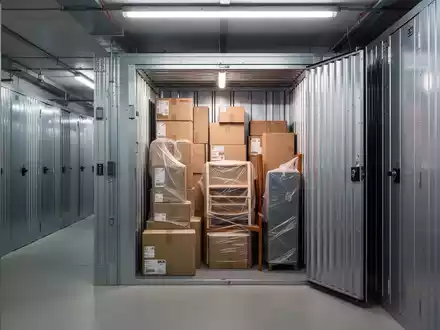 Ein modernes, sauberes Self-Storage-Lager in Berlin mit Reihen von Lagereinheiten und einem geöffneten Abteil mit Umzugskartons. - Foto: über boerse-global.de