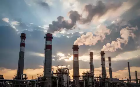 Industrieschornsteine, die sauberen Dampf vor einem dramatischen Himmel ausstoßen, symbolisieren Umweltauflagen und technologischen Wandel. - Foto: über boerse-global.de