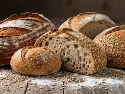 Nahaufnahme verschiedener gesunder Brotsorten, darunter Sauerteig- und Vollkornbrot, appetitlich auf einem Holztisch arrangiert. - Foto: über boerse-global.de