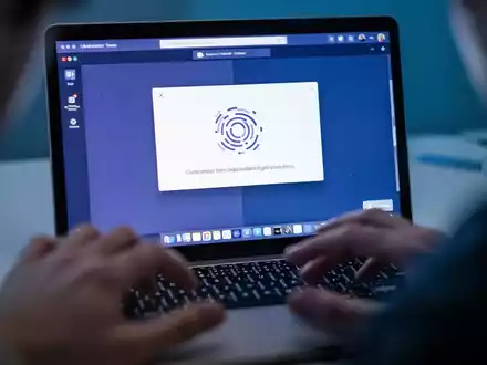 Nahaufnahme eines Laptop-Bildschirms mit einer Microsoft Teams-Fehlermeldung, HĂ€nde ĂŒber der Tastatur. - Foto: ĂŒber boerse-global.de