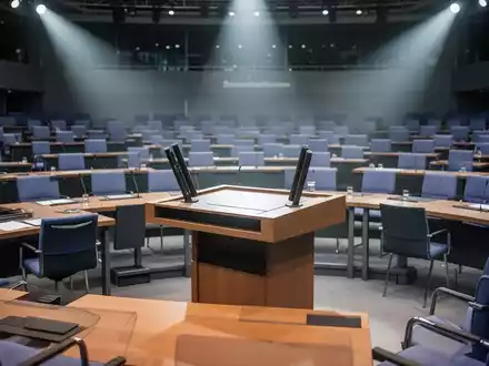 Der Plenarsaal des Deutschen Bundestags mit leerem Rednerpult, symbolisiert parlamentarische Entscheidungen und Sparmaßnahmen im Gesundheitswesen. - Foto: über boerse-global.de