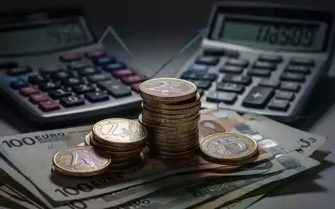 Ein Stapel Euromünzen und -scheine mit einem Taschenrechner im Hintergrund, der steigende Zahlen anzeigt. - Foto: über boerse-global.de
