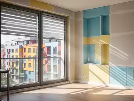 Ein modernes Apartment-Interieur an einem heißen Tag, mit sichtbaren Außenbeschattungssystemen und hellem Tageslicht, das auf einen kühlen Raum fällt. - Foto: über boerse-global.de