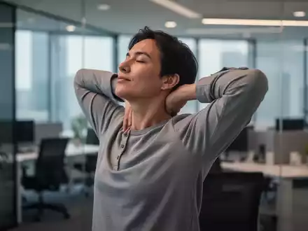 Eine Person dehnt im Büro vorsichtig Nacken und Schultern, um Verspannungen vorzubeugen. - Foto: über boerse-global.de