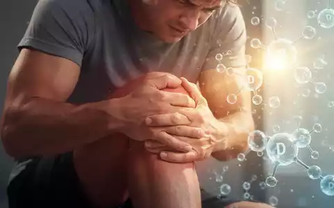 Eine Person mit Muskelschmerzen, die sich an den Arm fasst, mit angedeutetem Sonnenlicht im Hintergrund, das Vitamin D symbolisiert. - Foto: über boerse-global.de