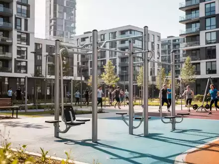 Moderne Outdoor-Fitnessgeräte in einem Park eines Neubaugebiets, umgeben von zeitgenössischen Wohngebäuden, mit sportlich aktiven Menschen. - Foto: über boerse-global.de
