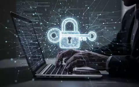 Schattenhafte Hände tippen auf Laptop, Bildschirm zeigt leuchtendes Schloss- und Schlüsselsymbol für digitale Sicherheitsbedrohung. - Foto: über boerse-global.de