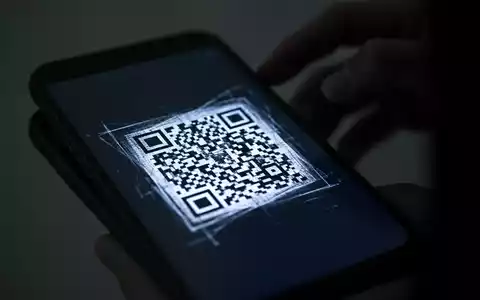 Nahaufnahme eines Smartphone-Bildschirms mit defektem QR-Code, verschwommene, schattige Hand im Hintergrund. - Foto: über boerse-global.de