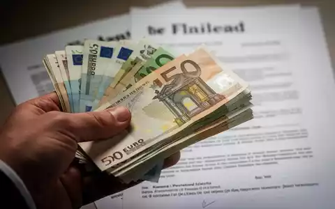 Eine Hand hält einen Stapel Euro-Banknoten, im Hintergrund verschwommen ein juristisches Dokument oder Testament. - Foto: über boerse-global.de