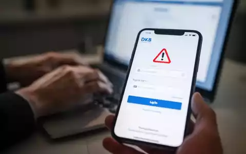 Smartphone mit gefälschter DKB-Loginseite, unscharfe Hände tippen im Hintergrund auf Laptop, Phishing-Betrug. - Foto: über boerse-global.de