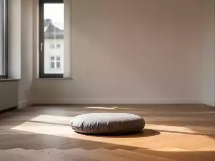 Ein ruhiger Meditationsraum in München mit einem einzelnen Kissen auf dem Boden, beleuchtet von sanftem, natürlichem Licht. - Foto: über boerse-global.de