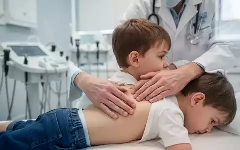 Eine Kinderärztin untersucht den Rücken eines Kindes mit sanften, osteopathischen Techniken in einer modernen Klinik. - Foto: über boerse-global.de